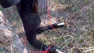 לאַוראַ אויף כילז מאָדעל שריט שוועסטער אין שוואַרץ קלייד און הויך כילז געבונדן און מאַסקט אין אַ האָלץ, האט צו זויגן אַ bdsm האָן.